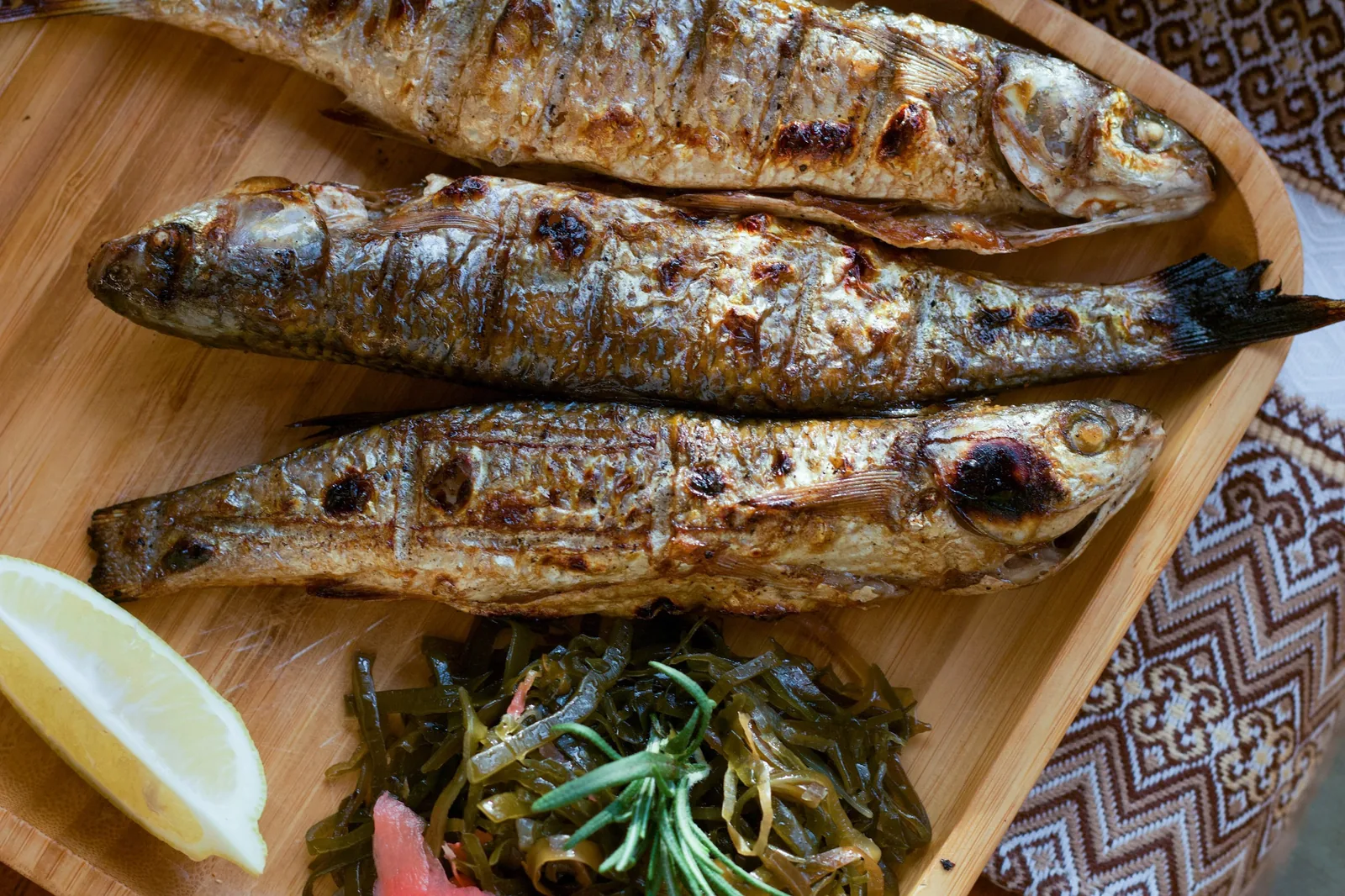 A wooden plate of grilled sardines with a slice of lemon (Málaga)